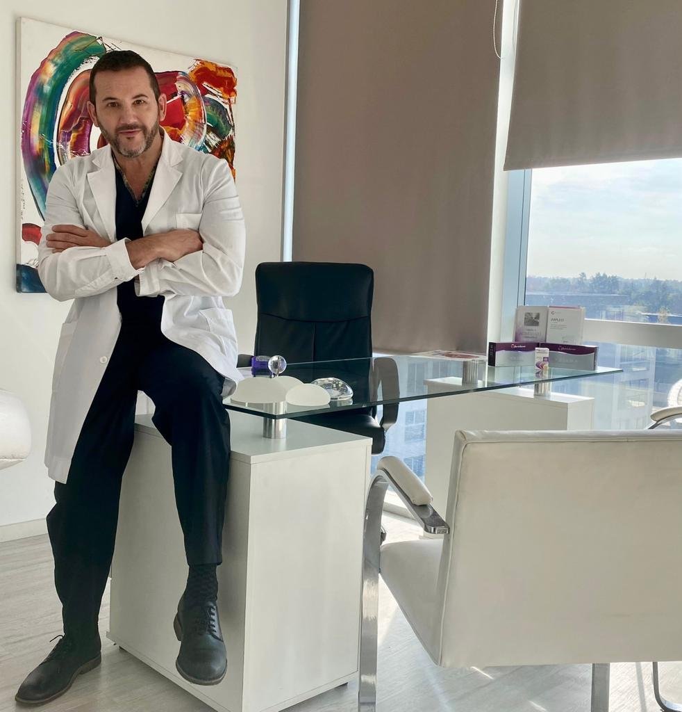 El Dr. Jorge Plotz sentado en su consultorio, con guardapolvo blanco y los brazos cruzados.