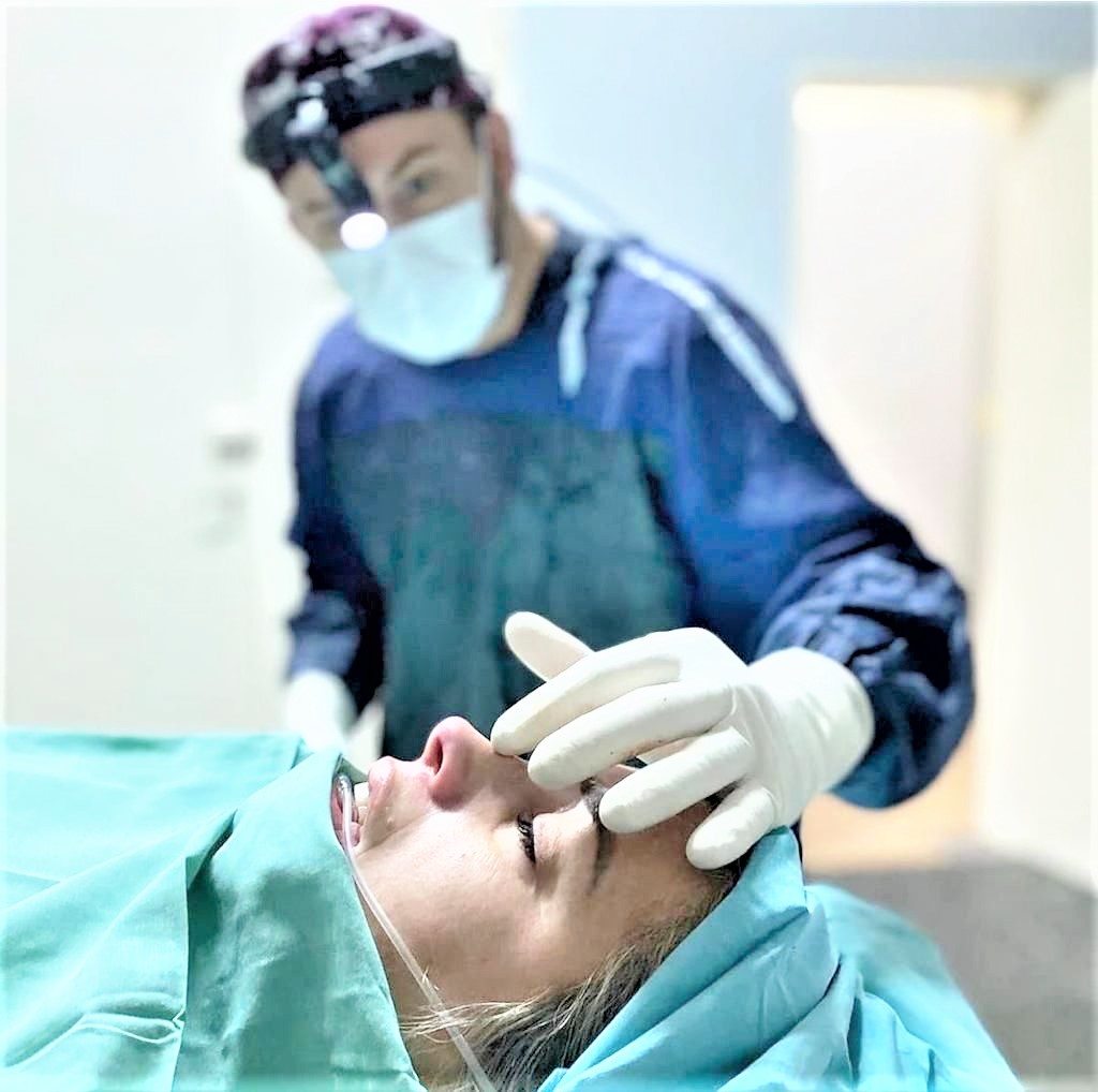 El Dr. Jorge Plotz con lupa quirúrgica y guantes, trabajando durante un procedimiento.